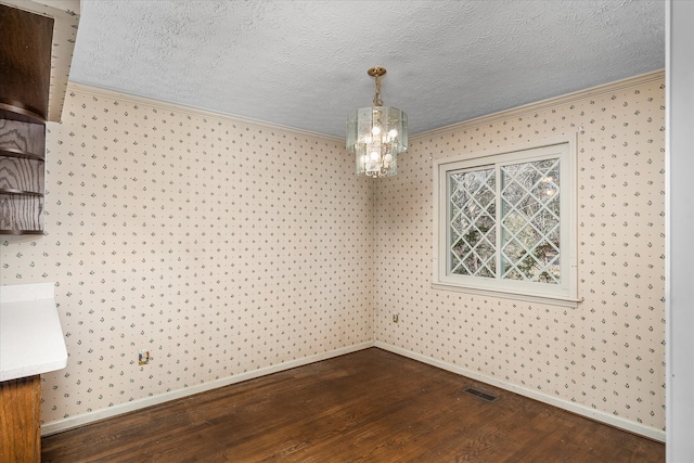 unfurnished dining area featuring hardwood / wood-style floors, a notable chandelier, ornamental molding, and a textured ceiling