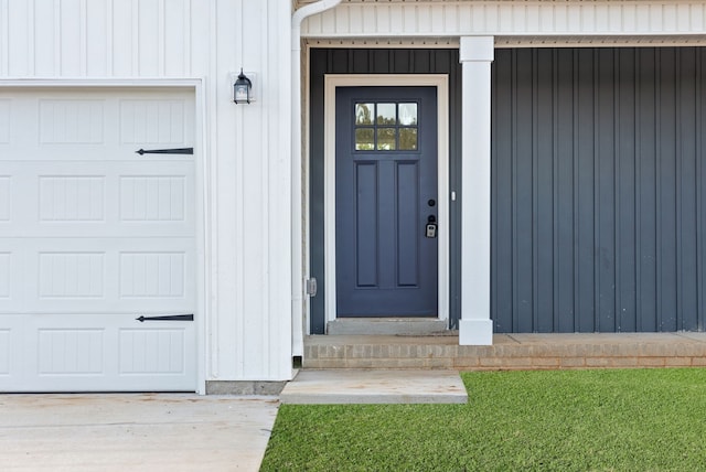 entrance to property featuring a lawn and a garage