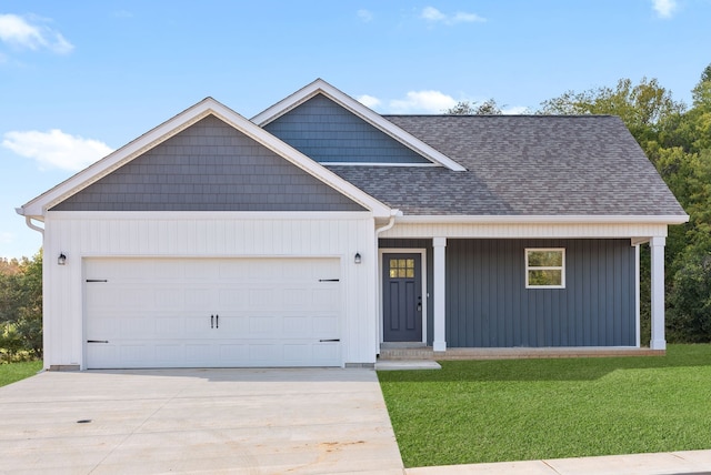 view of front of house featuring covered porch, a front yard, and a garage