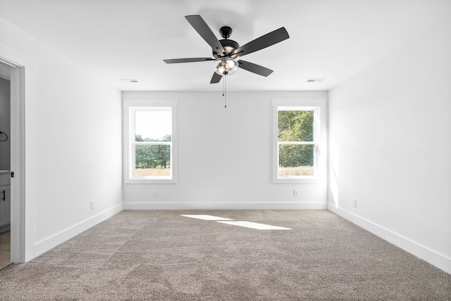 carpeted empty room with ceiling fan and plenty of natural light