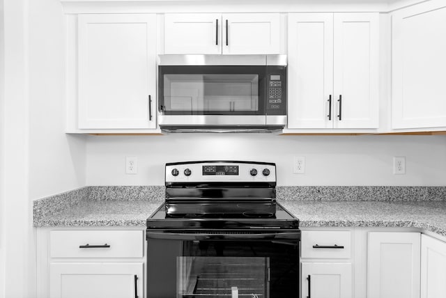 kitchen featuring light stone counters, white cabinetry, and stainless steel appliances