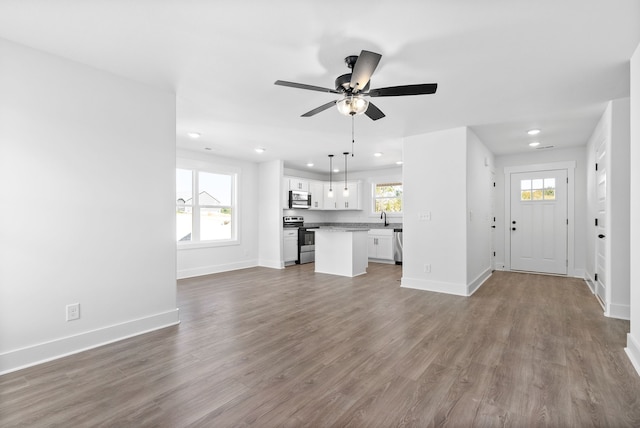 unfurnished living room featuring ceiling fan, hardwood / wood-style flooring, and sink