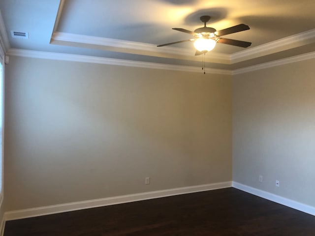 empty room with a raised ceiling, ornamental molding, and ceiling fan