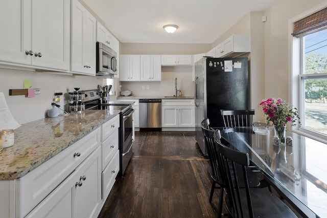 kitchen with sink, light stone counters, dark hardwood / wood-style floors, white cabinets, and appliances with stainless steel finishes