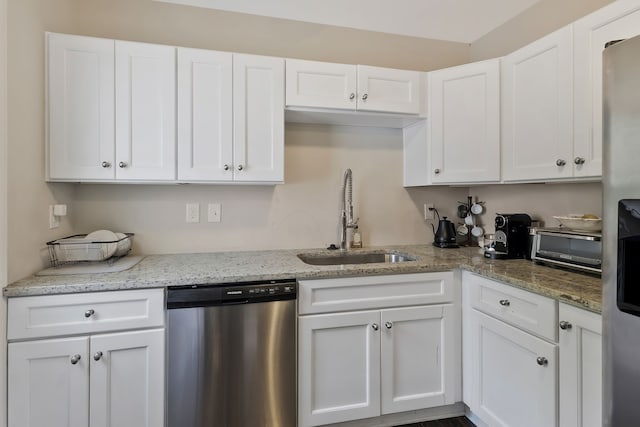 kitchen with light stone countertops, stainless steel appliances, sink, and white cabinetry