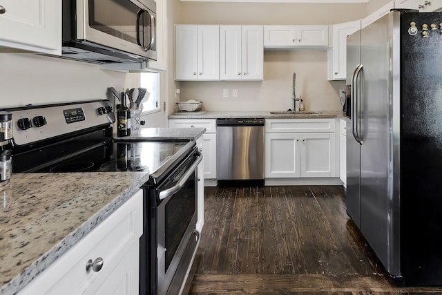 kitchen with light stone counters, white cabinets, dark wood-type flooring, sink, and appliances with stainless steel finishes