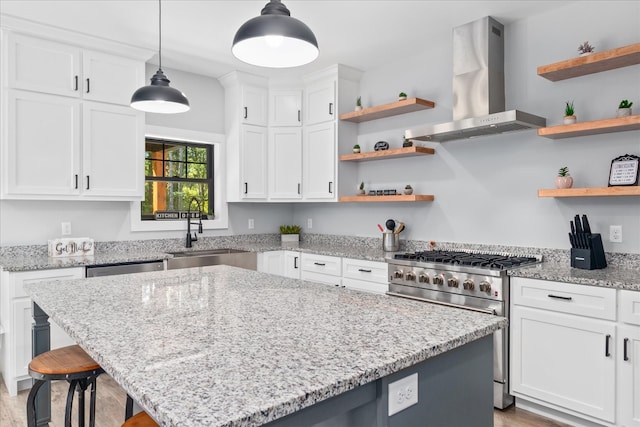 kitchen featuring exhaust hood, white cabinets, sink, appliances with stainless steel finishes, and decorative light fixtures