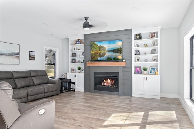 living room with ceiling fan, light hardwood / wood-style floors, and a large fireplace