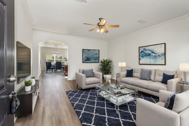 living room featuring ornamental molding, ceiling fan with notable chandelier, and hardwood / wood-style floors