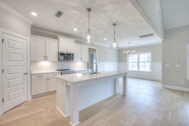 kitchen with range, sink, a center island with sink, and white cabinets