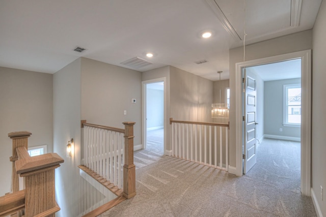 hallway with light carpet and an inviting chandelier