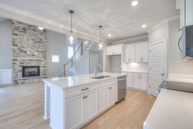 kitchen with sink, white cabinetry, decorative light fixtures, appliances with stainless steel finishes, and a kitchen island with sink