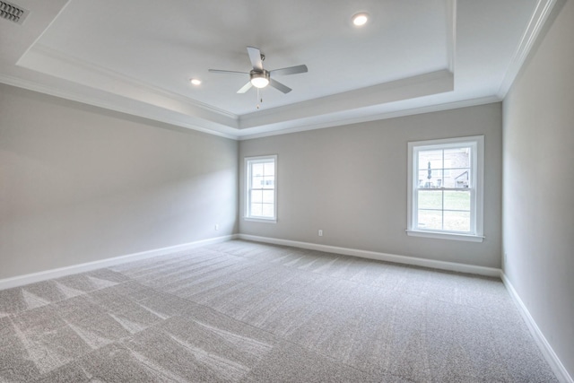 carpeted spare room with crown molding, ceiling fan, and a raised ceiling