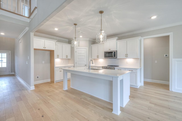 kitchen featuring white cabinetry, decorative light fixtures, sink, and a center island with sink