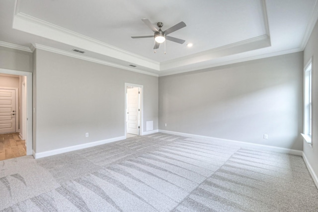 unfurnished room with crown molding, a tray ceiling, and light carpet