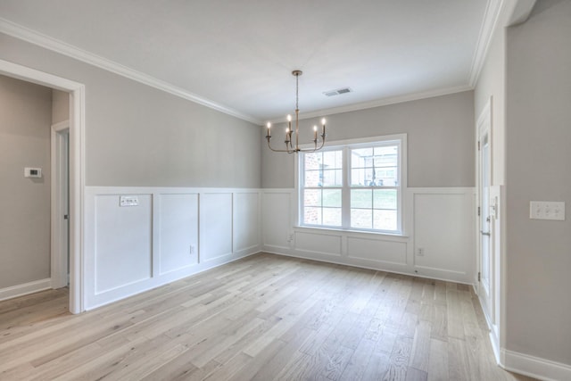 empty room with crown molding, light hardwood / wood-style floors, and a notable chandelier