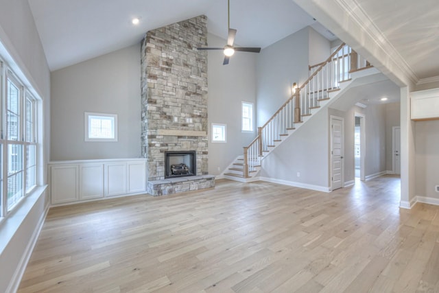 unfurnished living room featuring ornamental molding, a stone fireplace, high vaulted ceiling, and light wood-type flooring