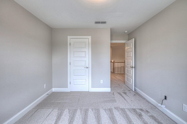 unfurnished bedroom featuring light carpet and a closet