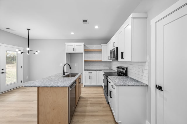 kitchen with white cabinets, an island with sink, light stone countertops, sink, and stainless steel appliances