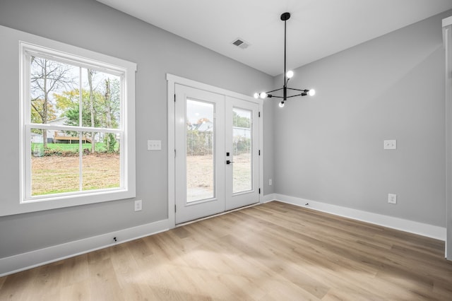 doorway featuring a wealth of natural light, a chandelier, light hardwood / wood-style floors, and french doors