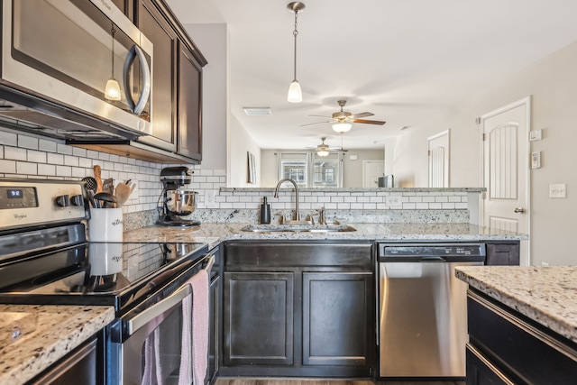 kitchen featuring sink, pendant lighting, appliances with stainless steel finishes, dark brown cabinets, and backsplash