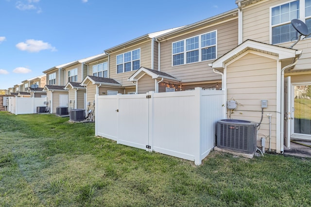 back of property featuring central AC unit and a yard