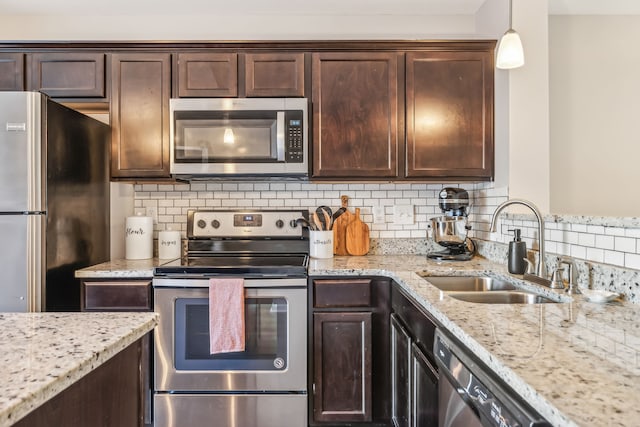 kitchen with decorative backsplash, hanging light fixtures, appliances with stainless steel finishes, and sink