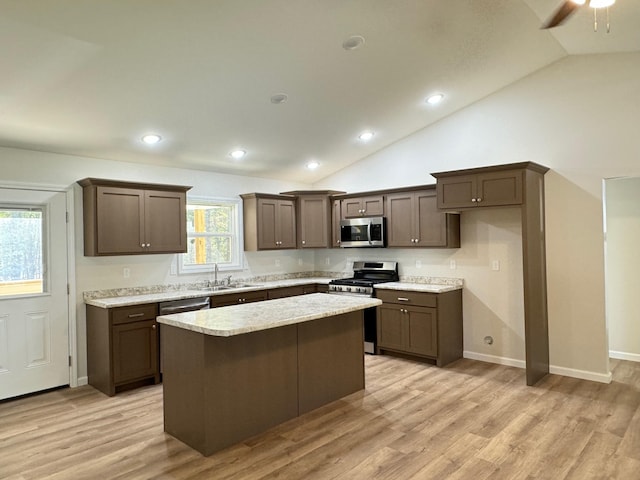 kitchen featuring lofted ceiling, sink, a kitchen island, stainless steel appliances, and light wood-type flooring