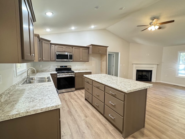 kitchen with sink, light hardwood / wood-style flooring, stainless steel appliances, a center island, and vaulted ceiling