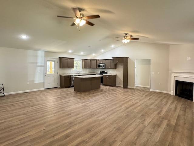 kitchen with lofted ceiling, ceiling fan, a center island, hardwood / wood-style floors, and stainless steel appliances