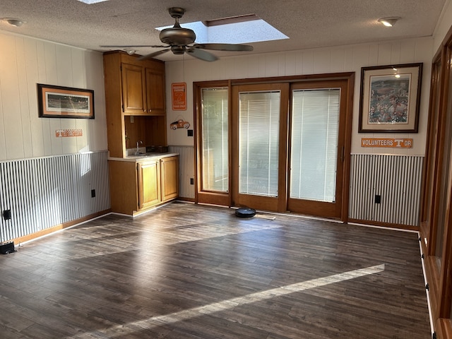 interior space with ceiling fan, sink, dark hardwood / wood-style flooring, wood walls, and a textured ceiling