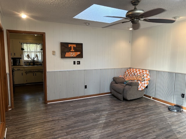 sitting room with dark hardwood / wood-style floors, a skylight, wooden walls, and a textured ceiling