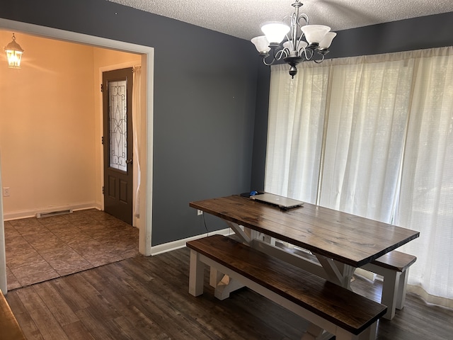 dining area with a chandelier, dark hardwood / wood-style flooring, and a textured ceiling