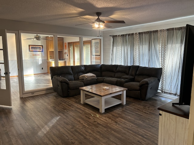 living room with ceiling fan, a textured ceiling, and dark hardwood / wood-style floors