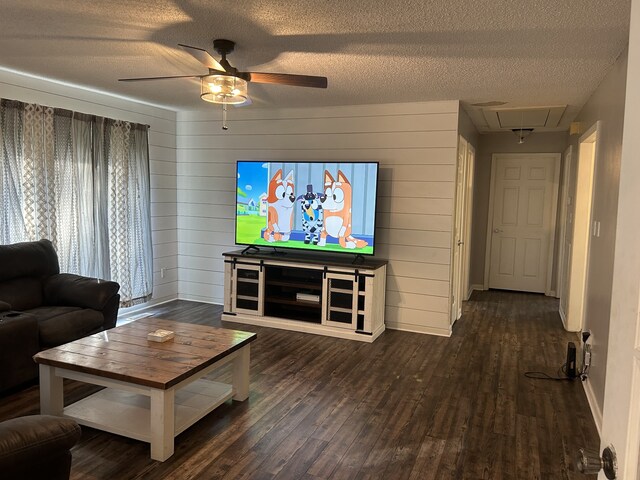 living room featuring ceiling fan, dark hardwood / wood-style floors, wooden walls, and a textured ceiling