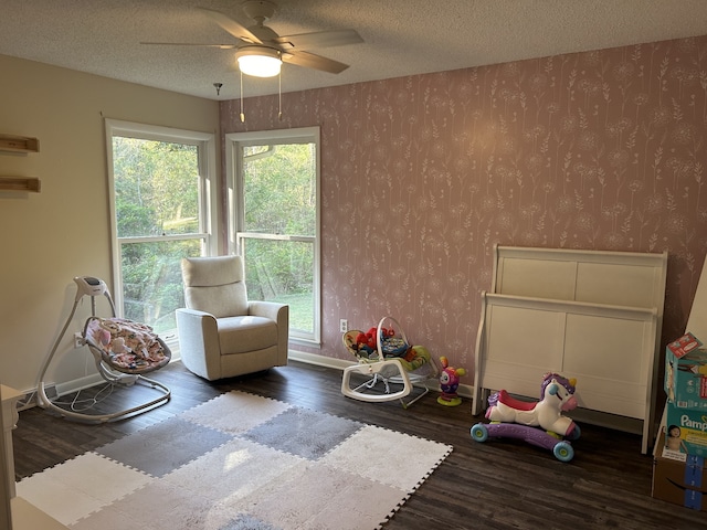 recreation room with dark wood-type flooring, ceiling fan, and a textured ceiling