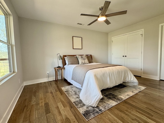 bedroom with a closet, dark hardwood / wood-style floors, and ceiling fan