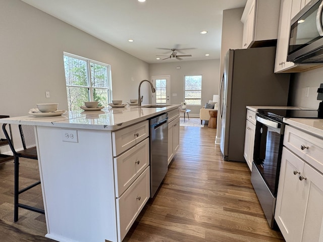 kitchen with a center island with sink, sink, stainless steel appliances, and white cabinets