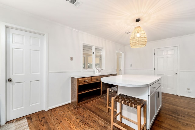 kitchen featuring pendant lighting, crown molding, dark wood-type flooring, a notable chandelier, and a center island