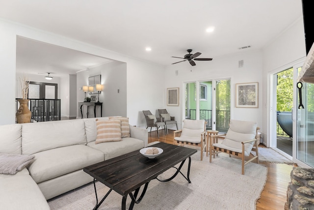 living room with ornamental molding, ceiling fan, and light hardwood / wood-style flooring