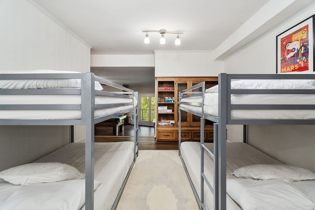 bedroom with wood walls, crown molding, and hardwood / wood-style floors