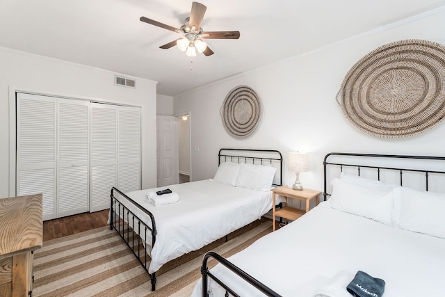 bedroom with ceiling fan, a closet, ornamental molding, and wood-type flooring