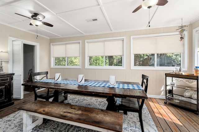 dining space featuring wood-type flooring, wooden walls, and ceiling fan