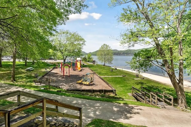 view of property's community with a playground, a yard, and a water view