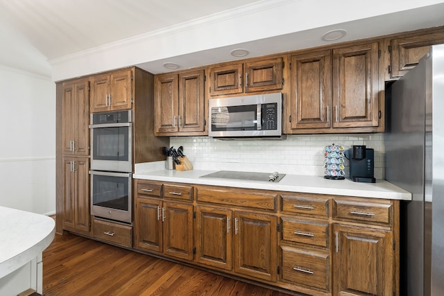 kitchen featuring stainless steel appliances, ornamental molding, tasteful backsplash, and dark hardwood / wood-style flooring