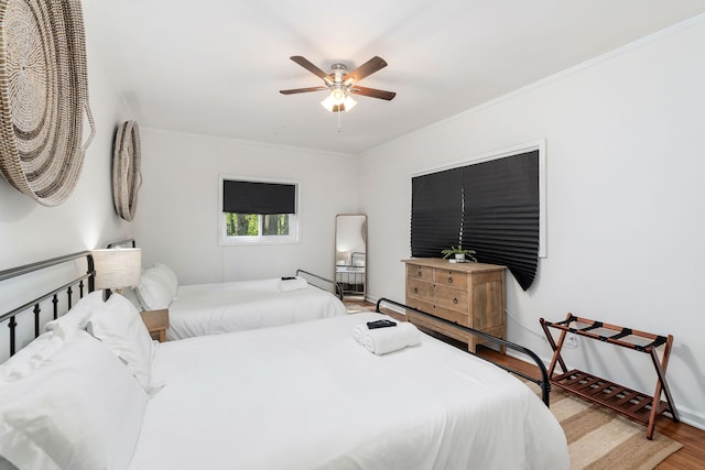 bedroom with ceiling fan, ornamental molding, and wood-type flooring