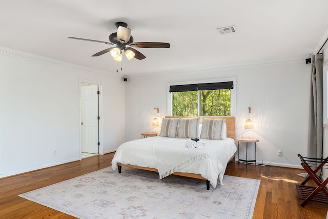 bedroom featuring wood-type flooring, ornamental molding, and ceiling fan