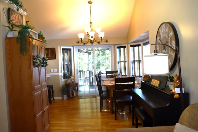 dining space featuring vaulted ceiling, an inviting chandelier, and hardwood / wood-style floors