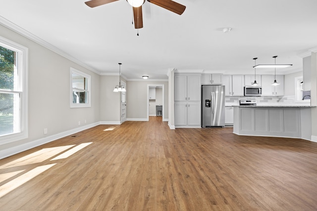 unfurnished living room with ceiling fan with notable chandelier, crown molding, and light hardwood / wood-style floors