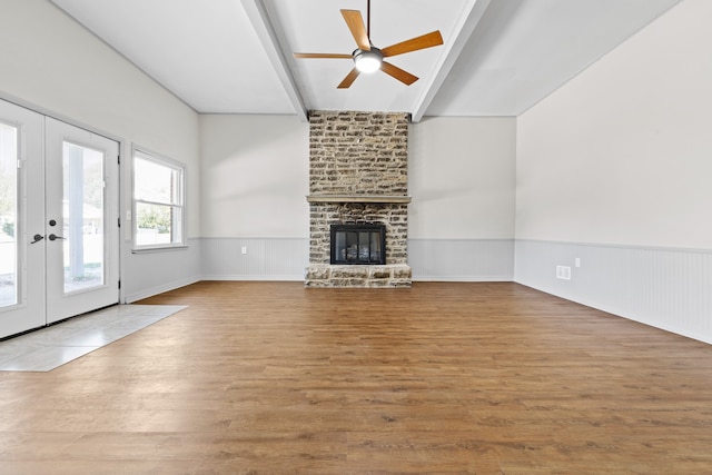 unfurnished living room featuring a fireplace, ceiling fan, hardwood / wood-style floors, and french doors